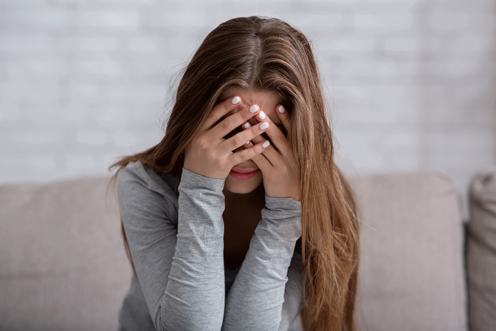 young woman looking distraught with her head in her hands asking herself what is the most common cause of a relapse