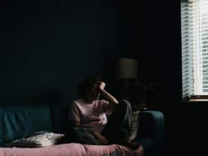 woman in purple dress sitting on couch isolating as a coping mechanism